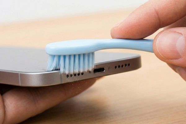 Ein Foto von der Unterseite, auf dem die Lautsprechergitter mit einer sauberen und weichen Bürste gereinigt werden.